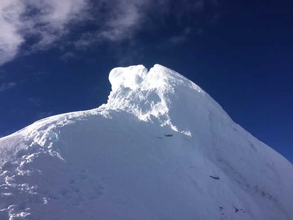 A wind-carved snow summit under a deep blue sky